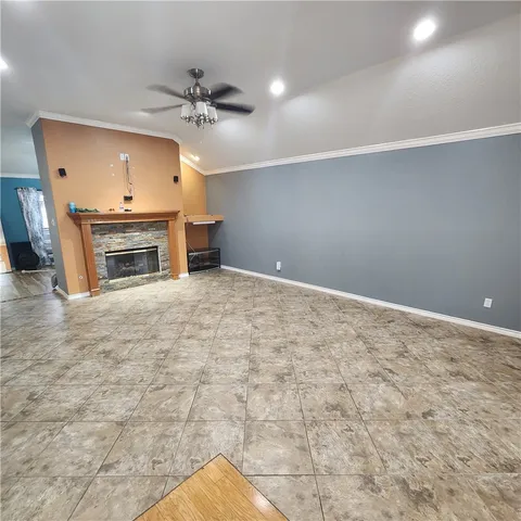 a view of a livingroom with a fireplace a ceiling fan and windows