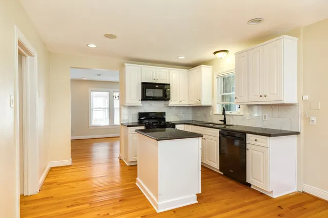 a kitchen with granite countertop a stove top oven a sink a counter space and cabinets