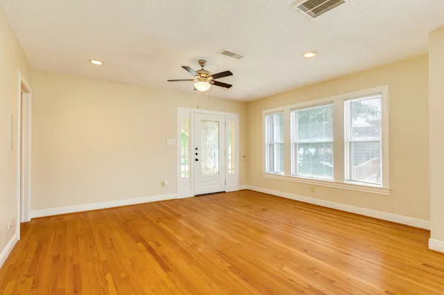 a view of an empty room with a window and wooden floor