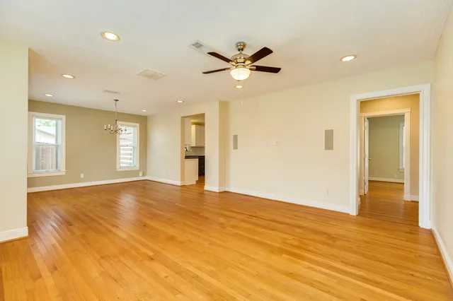 a view of an empty room with wooden floor and a window
