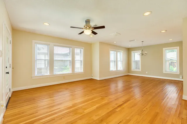 a view of an empty room with a window and wooden floor