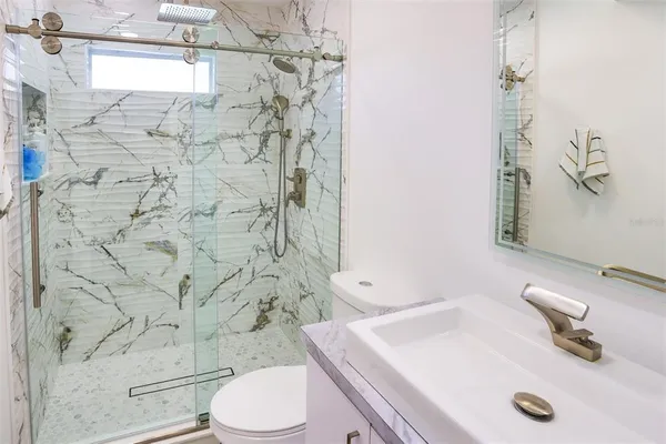 a bathroom with a sink a toilet a window and shower