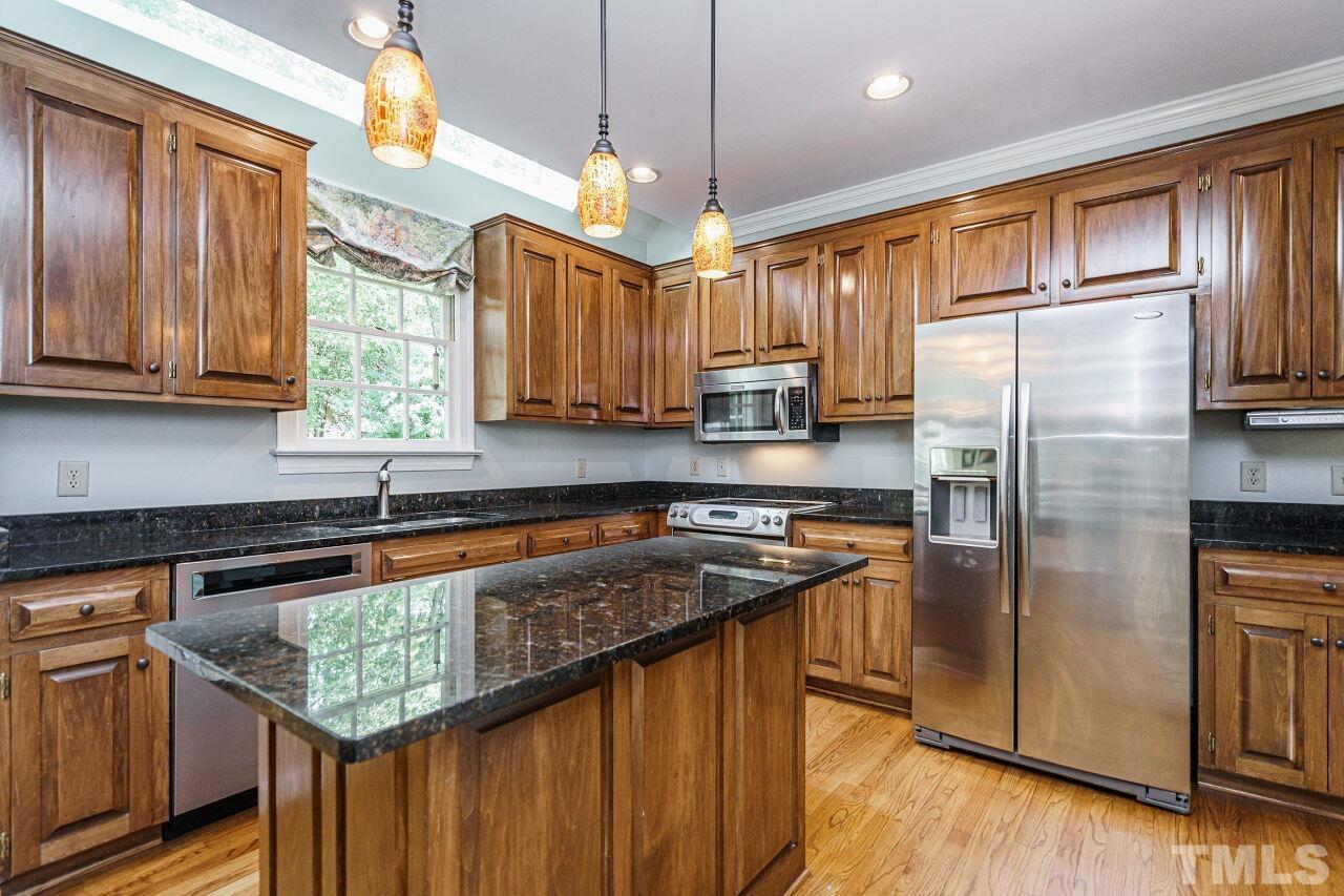 8601 Zinfandel Place Raleigh, NC 27615 - Photo 8 of 29 a kitchen with stainless steel appliances granite countertop a refrigerator a sink dishwasher a stove a dining table and chairs with wooden floor