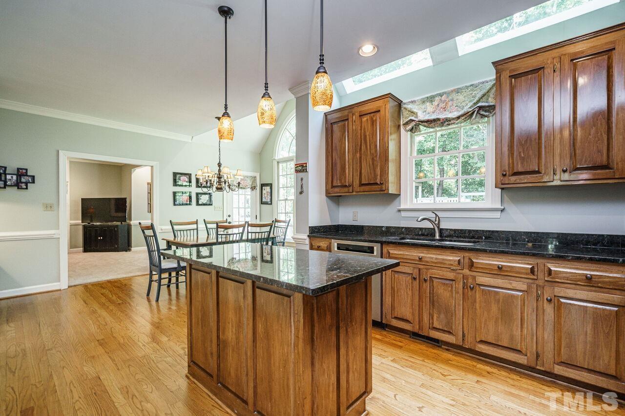 8601 Zinfandel Place Raleigh, NC 27615 - Photo 10 of 29 a kitchen with stainless steel appliances granite countertop wooden cabinets a sink dishwasher a dining table and chairs with wooden floor