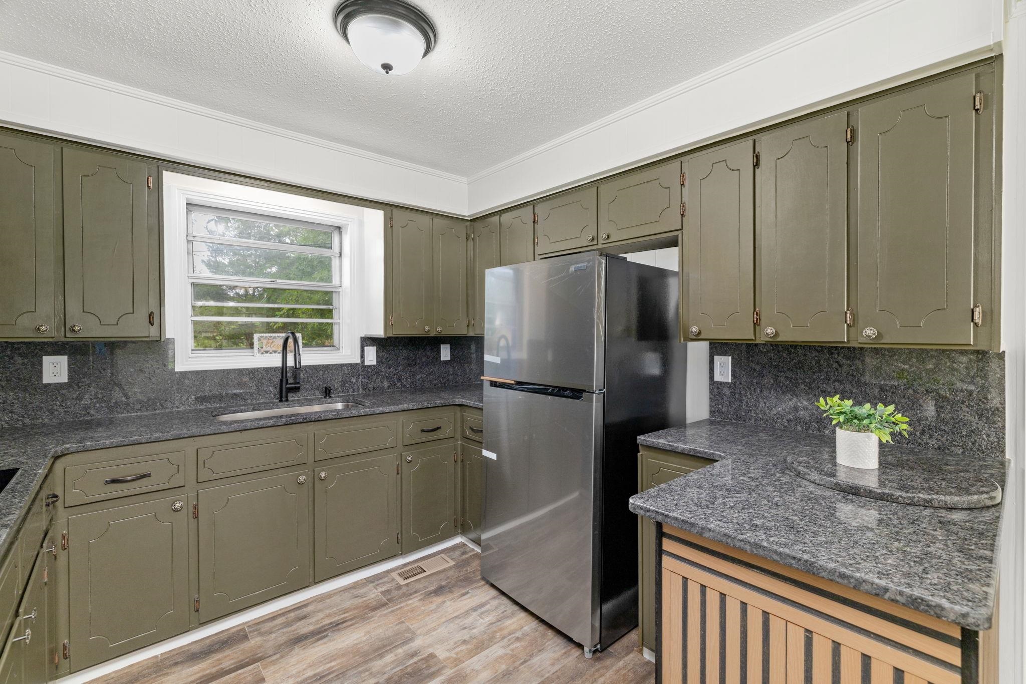 217 Red Bay Road Golden, MS 38847 - Photo 9 of 33 Kitchen featuring wood-finish flooring, dark stone countertops, and olive green cabinetry with decorative trim