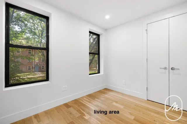 a view of an empty room with wooden floor and windows