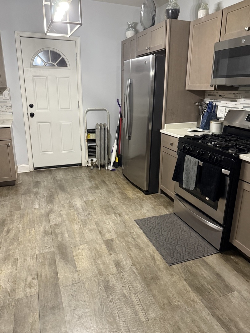 7825 South Paulina Street Chicago, IL 60620 - Photo 23 of 34 a kitchen with stainless steel appliances granite countertop a refrigerator a stove and a sink with wooden floor