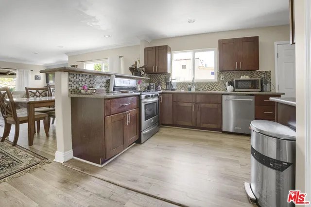 a kitchen with stainless steel appliances granite countertop a refrigerator a stove top oven a sink and dishwasher with wooden floor