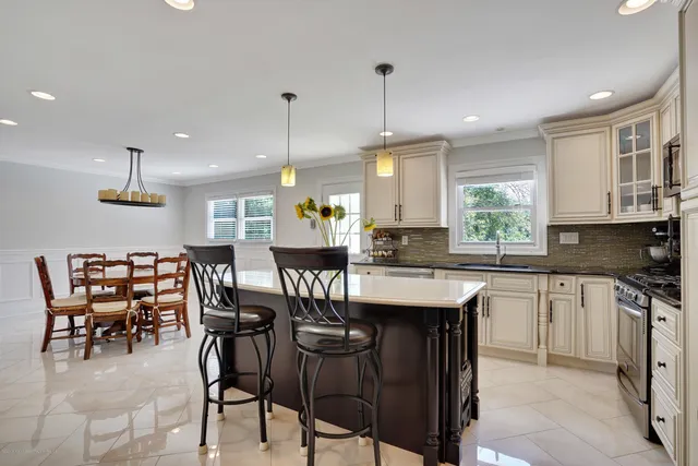 a kitchen with stainless steel appliances kitchen island granite countertop a table chairs stove and microwave