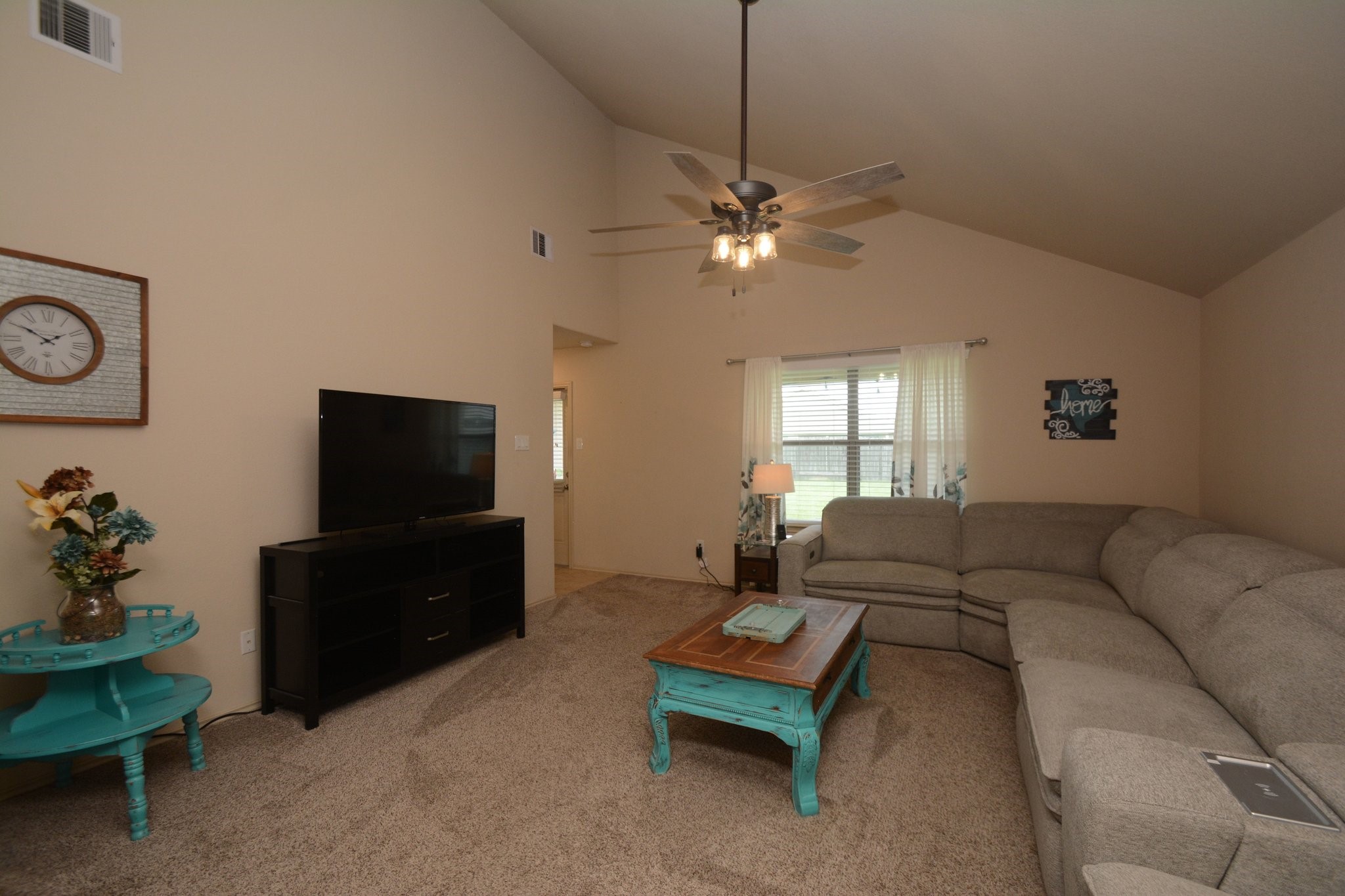 23318 Dukes Run Drive Spring, TX 77373 - Photo 18 of 41 Spacious living room with vaulted ceiling, neutral walls, and carpeted flooring. With room enough for a large sectional sofa, ceiling fan, and a TV setup. Natural light streams in through the window, complementing the cozy ambiance.