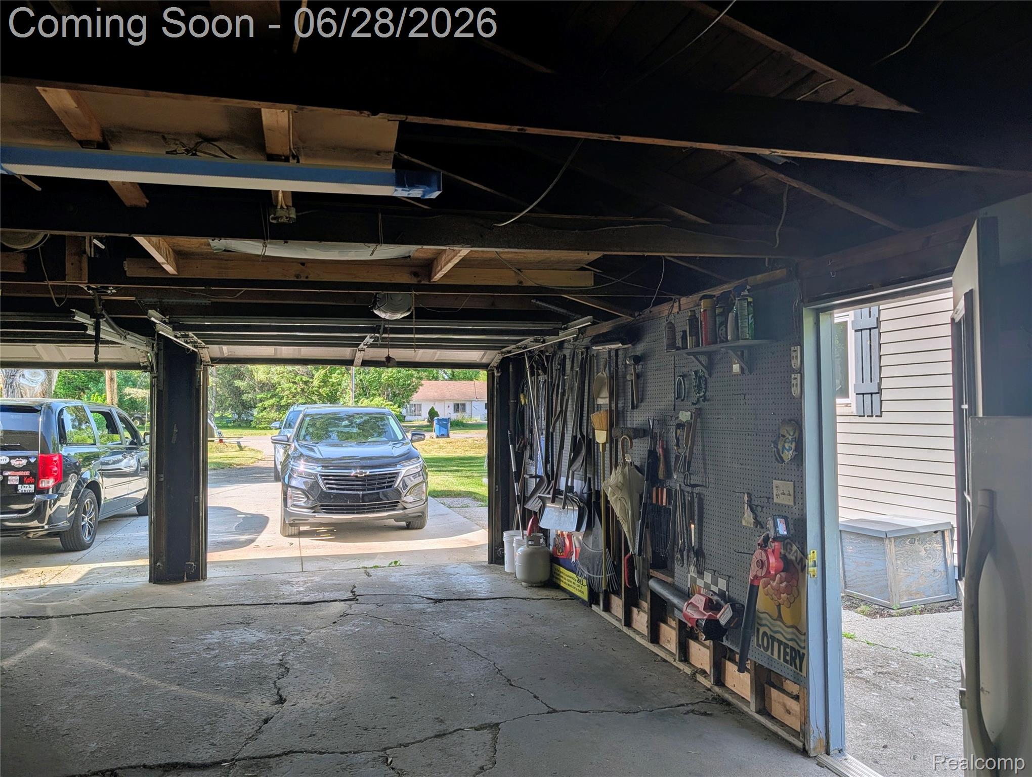 4456 East Coldwater Road Flint, MI 48506 - Photo 33 of 35 Attached garage with an exposed beam ceiling, concrete flooring, and built-in shelving and pegboard storage