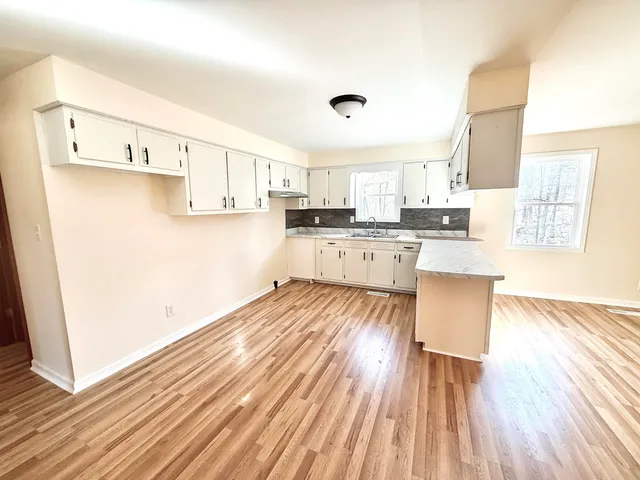 a view of a livingroom with a chandelier fan and wooden floor