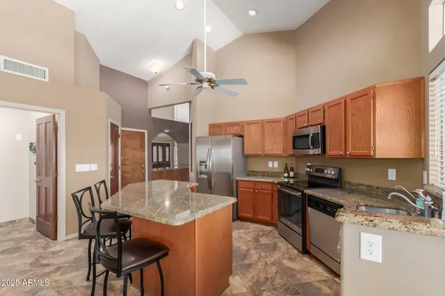 a kitchen with stainless steel appliances granite countertop a stove top oven a sink a dining table and chairs