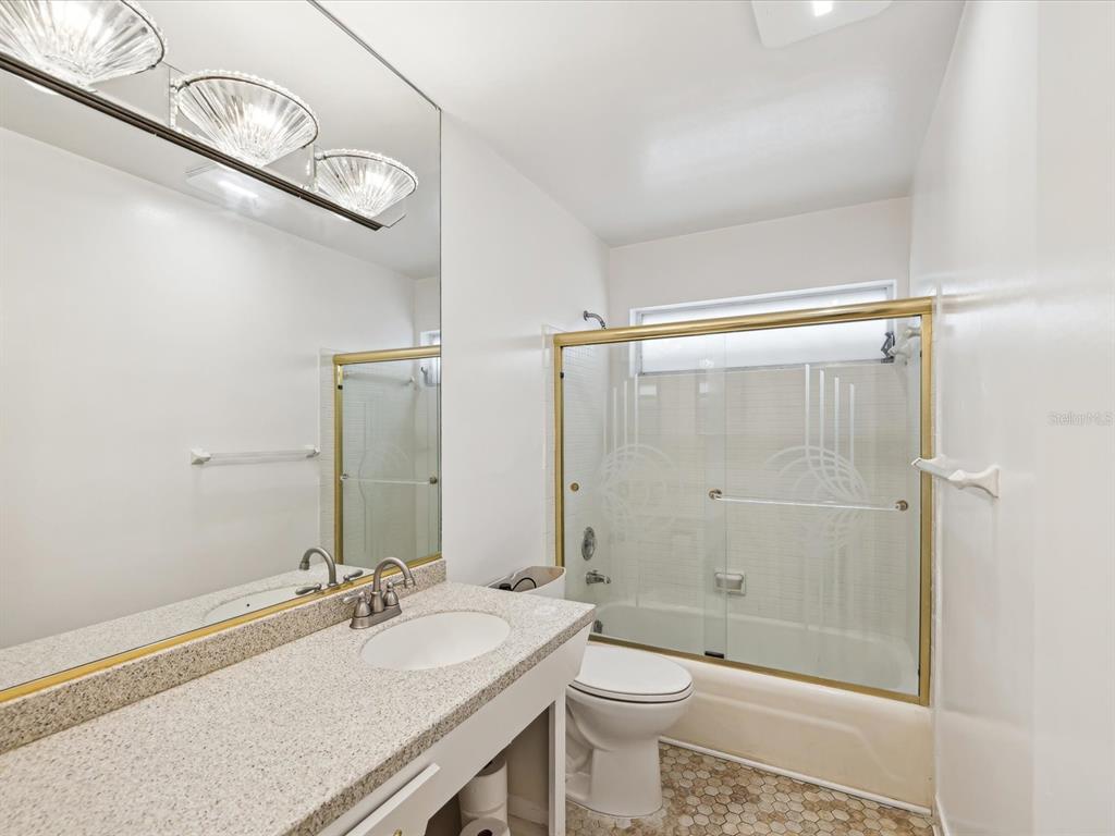 11549 48th Avenue North St. Petersburg, FL 33708 - Photo 36 of 37 a bathroom with a granite countertop sink a toilet a mirror and shower