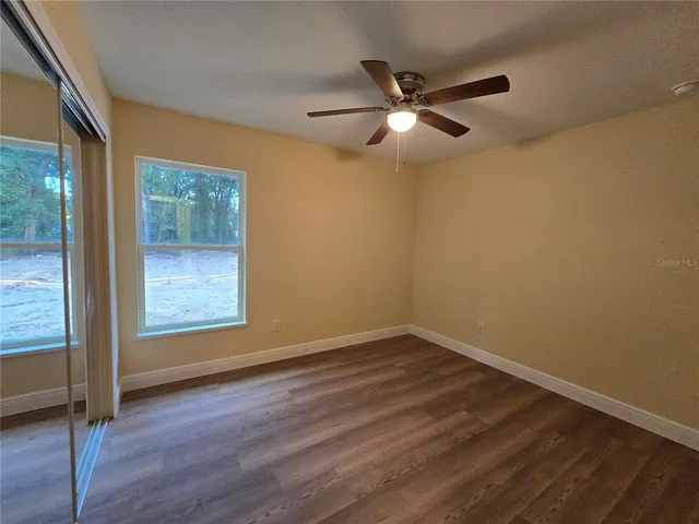 an empty room with wooden floor fan and window