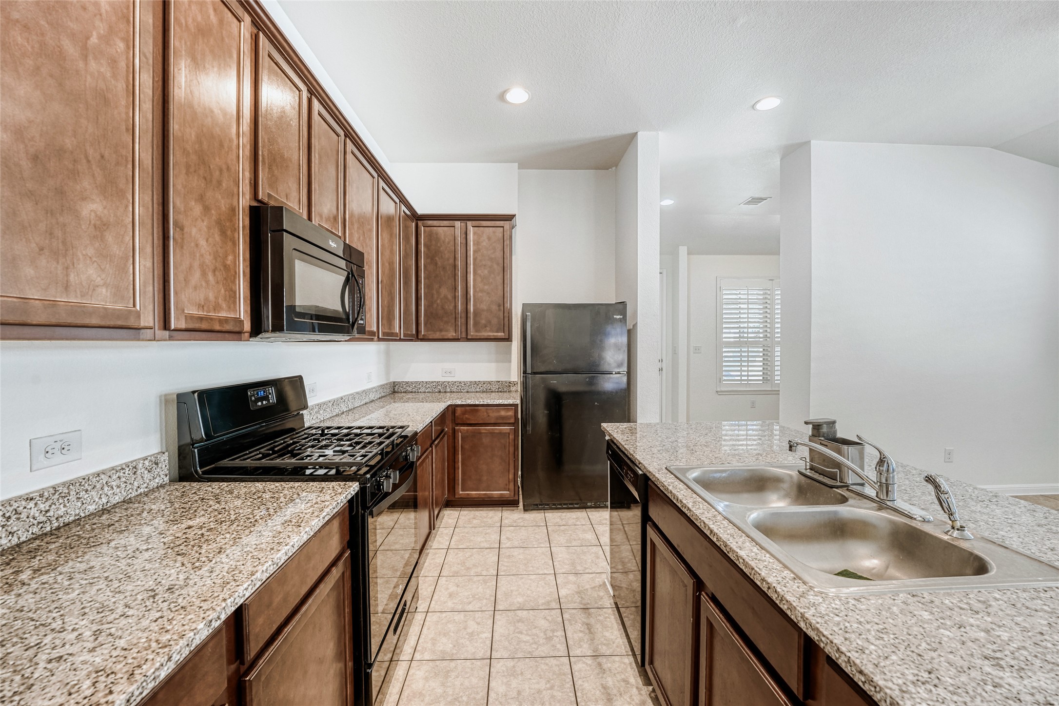 410 Anacua Loop, Unit 30 Manchaca, TX 78652 - Photo 12 of 33 Kitchen with black appliances, light tile patterned floors, recessed lighting, light stone counters, and vaulted ceiling