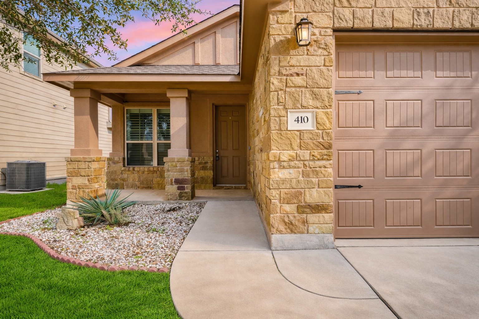 410 Anacua Loop, Unit 30 Manchaca, TX 78652 - Photo 9 of 33 Exterior entry at dusk with stone siding and covered porch