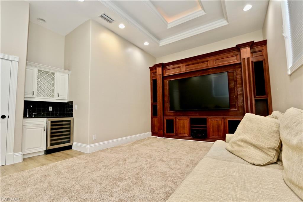 2855 Coach House Way Naples, FL 34105 - Photo 13 of 42 Living room featuring wine cooler, recessed lighting, light colored carpet, wet bar, and a raised ceiling