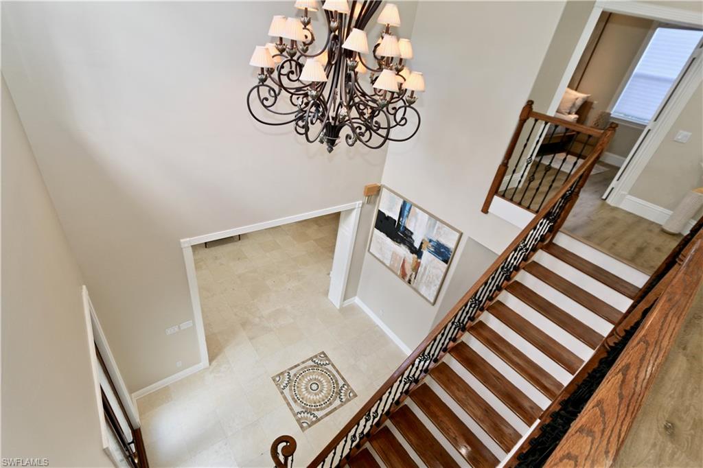 2855 Coach House Way Naples, FL 34105 - Photo 14 of 42 Stairway with hanging lights and a high ceiling