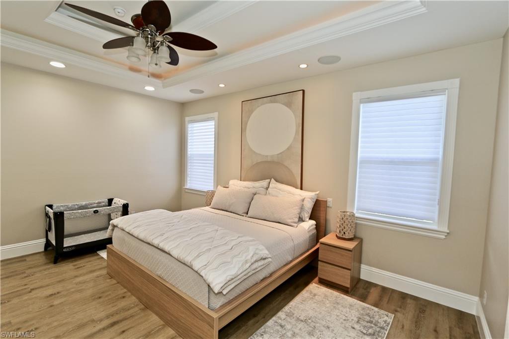 2855 Coach House Way Naples, FL 34105 - Photo 27 of 42 Bedroom with wood finished floors, recessed lighting, crown molding, ceiling fan, and a tray ceiling