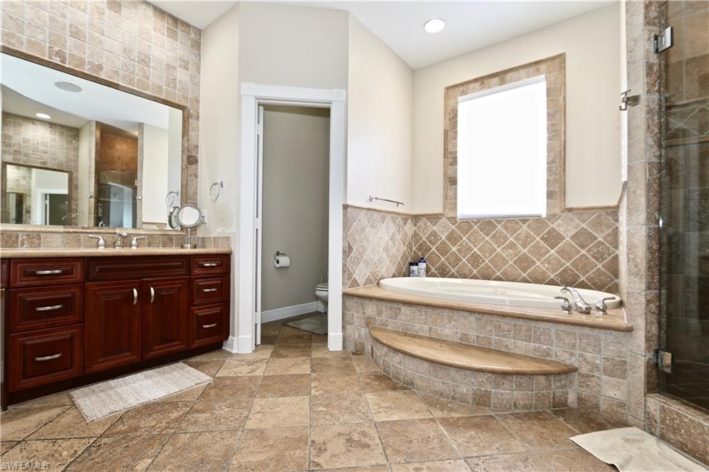 2855 Coach House Way Naples, FL 34105 - Photo 31 of 42 Bathroom with vanity, a bath, a shower stall, stone tile flooring, and recessed lighting