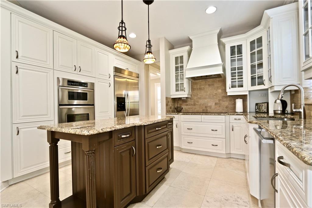 2855 Coach House Way Naples, FL 34105 - Photo 38 of 42 Kitchen featuring two tone color scheme, light stone counters, stainless steel appliances, a center island, and decorative light fixtures
