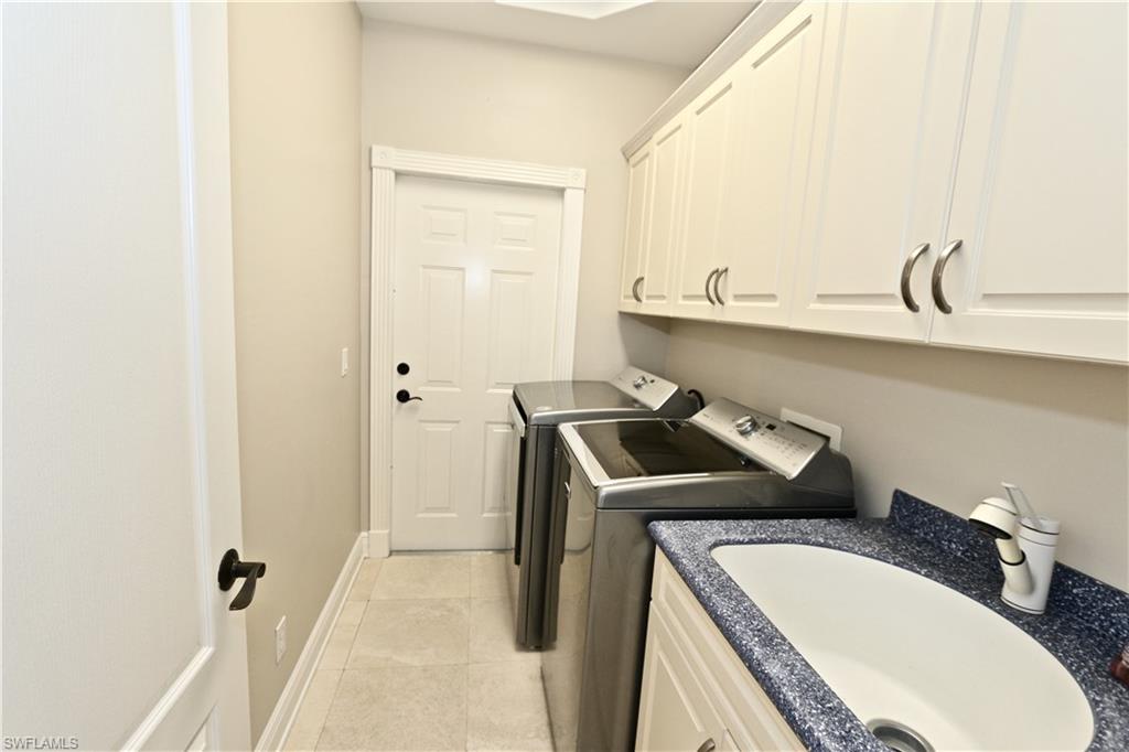 2855 Coach House Way Naples, FL 34105 - Photo 40 of 42 Laundry area featuring washer and clothes dryer, cabinet space, and light tile patterned flooring