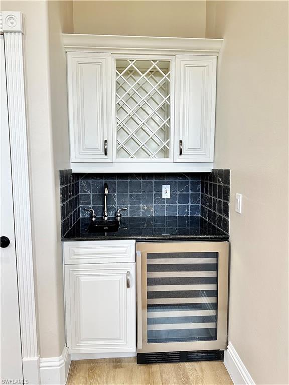 2855 Coach House Way Naples, FL 34105 - Photo 10 of 42 Indoor wet bar featuring dark stone counters, beverage cooler, and white cabinetry