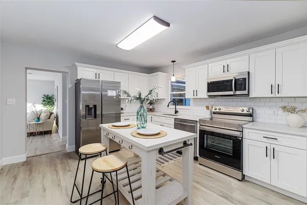 a kitchen with stainless steel appliances granite countertop a stove a sink dishwasher a refrigerator with a dining table and chairs
