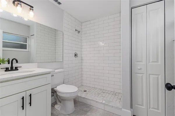 a bathroom with a toilet a sink a mirror and shower