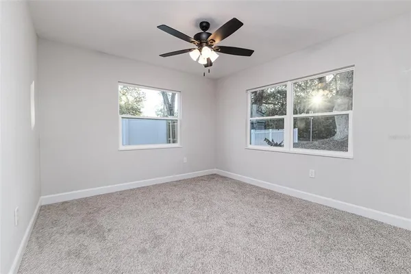 an empty room with windows and ceiling fan
