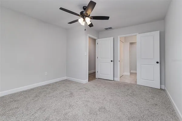 an empty room with closet and a ceiling fan