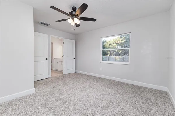 an empty room with windows and fan