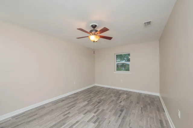 an empty room with wooden floor and fan