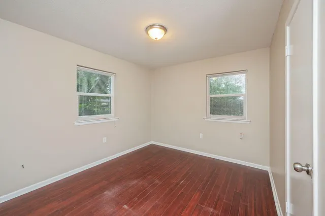 an empty room with a window and wooden floor