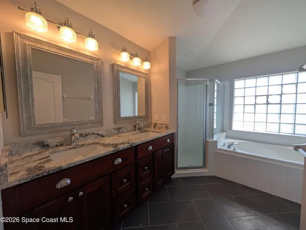 a spacious bathroom with a granite countertop tub sink double and mirror