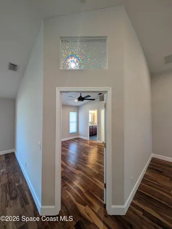 a view of a hallway with wooden floor and a living room