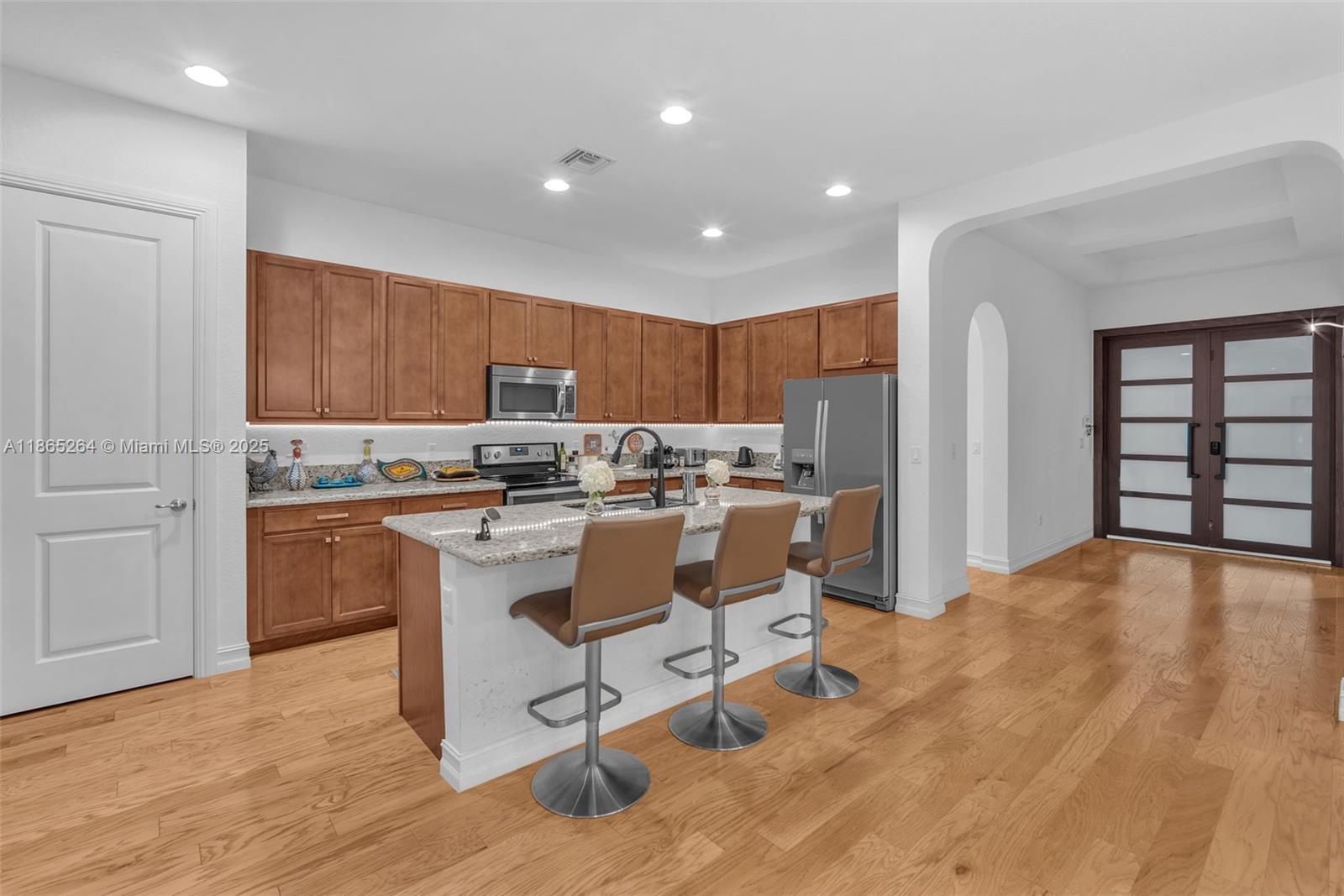 1281 Southwest 113th Way, Unit 1281 Pembroke Pines, FL 33025 - Photo 12 of 38 a kitchen with kitchen island granite countertop wooden cabinets and refrigerator