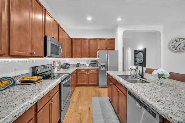 a kitchen with granite countertop stainless steel appliances a sink stove top oven and cabinets