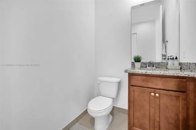 a bathroom with a granite countertop toilet and a sink