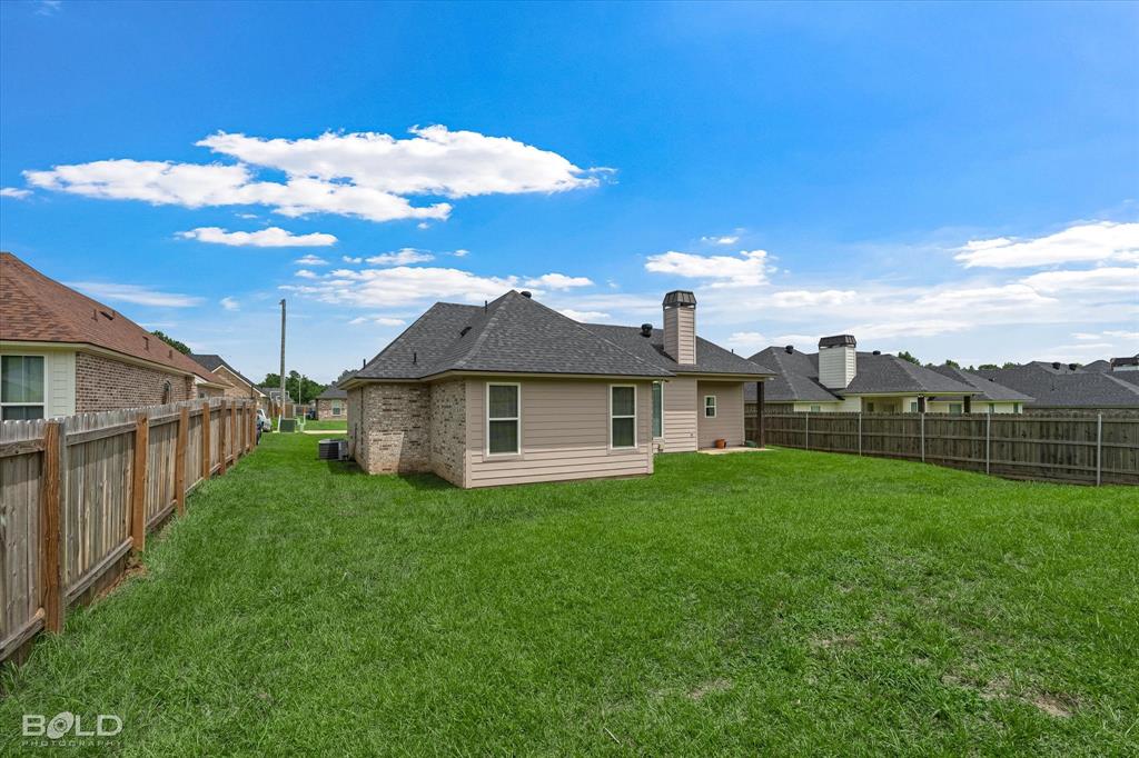 6896 Bethany Reed Circle Blanchard, LA 71107 - Photo 10 of 37 Expansive grassy backyard featuring perimeter wood fencing, a brick and siding exterior, and a visible chimney