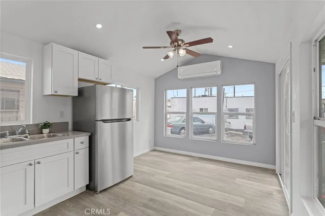 a kitchen with stainless steel appliances a refrigerator a sink cabinets and wooden floor