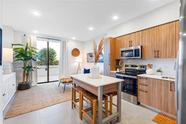 a open kitchen with stainless steel appliances granite countertop a stove top oven a sink dishwasher a dining table and chairs with wooden floor