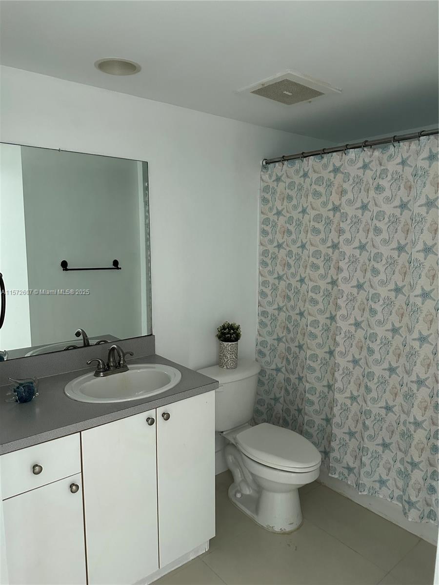 9201 Collins Avenue, Unit 524 Surfside, FL 33154 - Photo 14 of 20 a bathroom with a granite countertop sink a toilet and a mirror