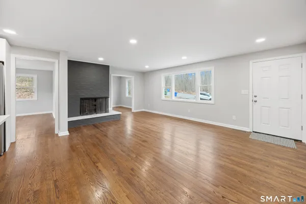 an empty room with wooden floor fire place and windows