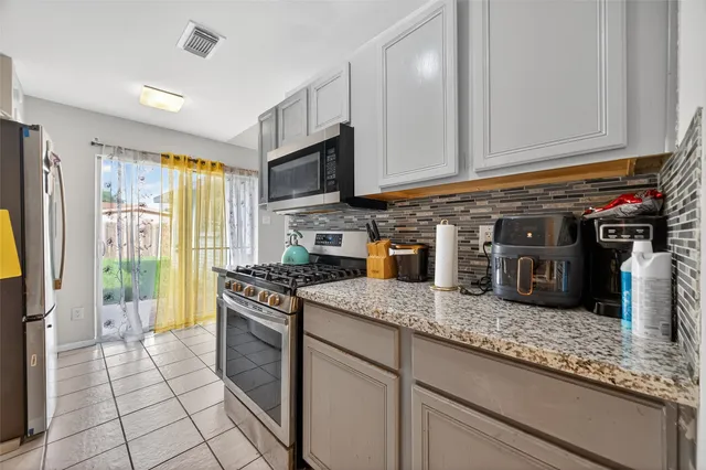 a kitchen with stainless steel appliances granite countertop a stove a sink and a microwave