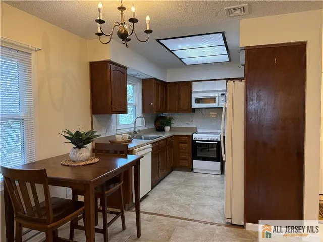 a kitchen with a chandelier stainless steel appliances and cabinets