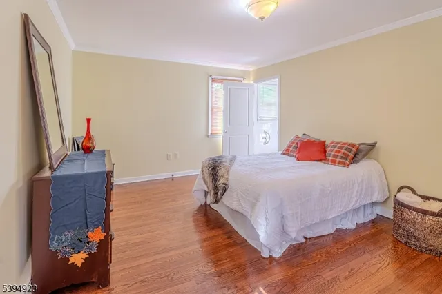 a bedroom with a bed and a dresser with wooden floor