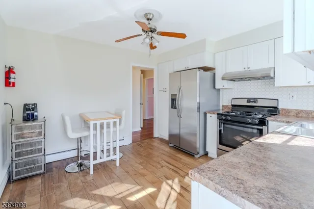 a kitchen with stainless steel appliances granite countertop a stove a refrigerator and a refrigerator with white cabinets