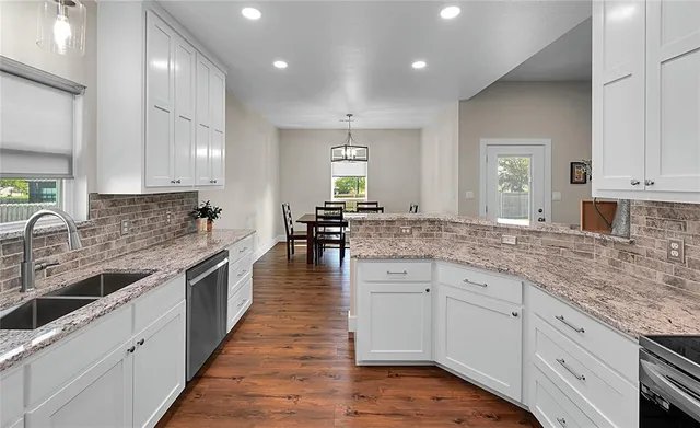 a large kitchen with granite countertop a sink and cabinets